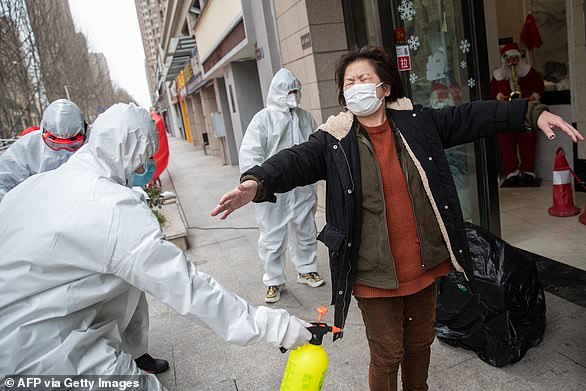 A woman who has recovered coronavirus is disinfected as she arrives at a hotel for a 14-day quarantine after being discharged from a hospital in Wuhan
