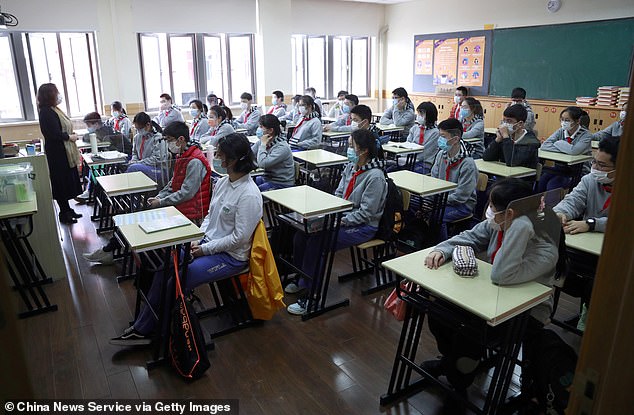 The news comes as the city of Wuhan, where the global coronavirus pandemic began in December, yesterday discharged its last COVID-19 patient, health officials said. Pictured, students wearing face masks have a class at a middle school in Shanghai on April 27