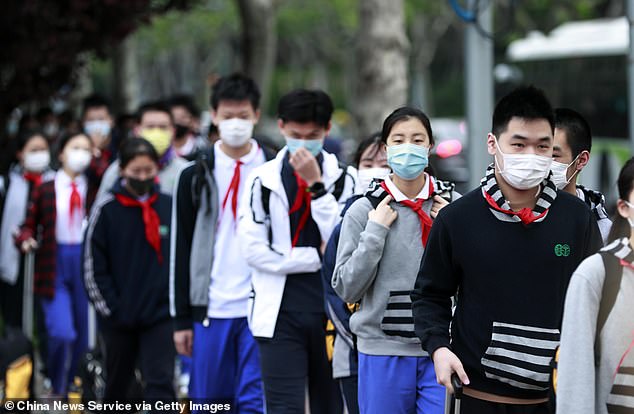Tens of thousands of graduating students in China have returned to the campus after spending three months at home due to coronavirus. Pictured, students wearing face masks line up to have their temperature checked at the entrance of a middle school in Shanghai on April 27