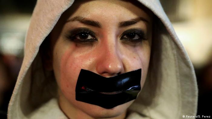 Woman with hood and tape across her mouth (Reuters/S. Perez)